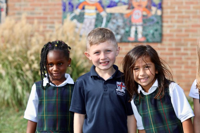 Three Royalmont elementary students smiling together outside the school.